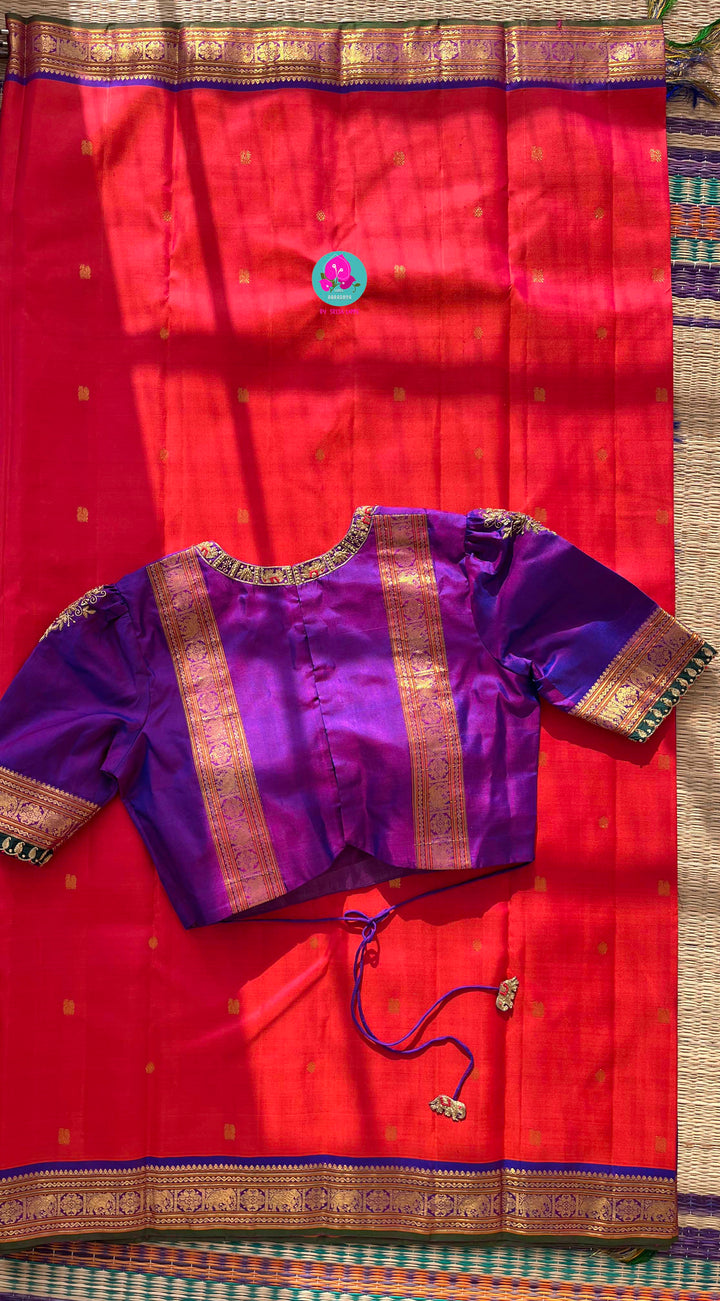 Pinkish shade of red with deep purple border Kanchipuram silk Saree paired with hand embroidered blouse